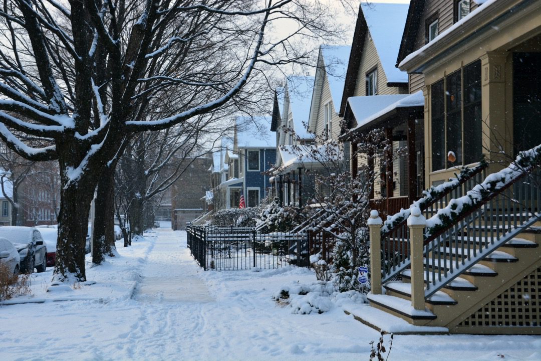Snow covered sidewalk in front of homes