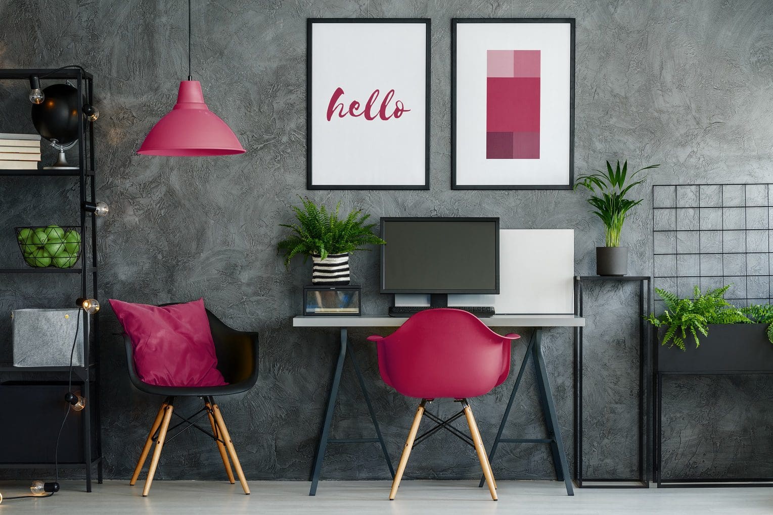 luxury home office ideas team logue Cherry pink chair at desk with desktop in dark home office with posters on concrete wall