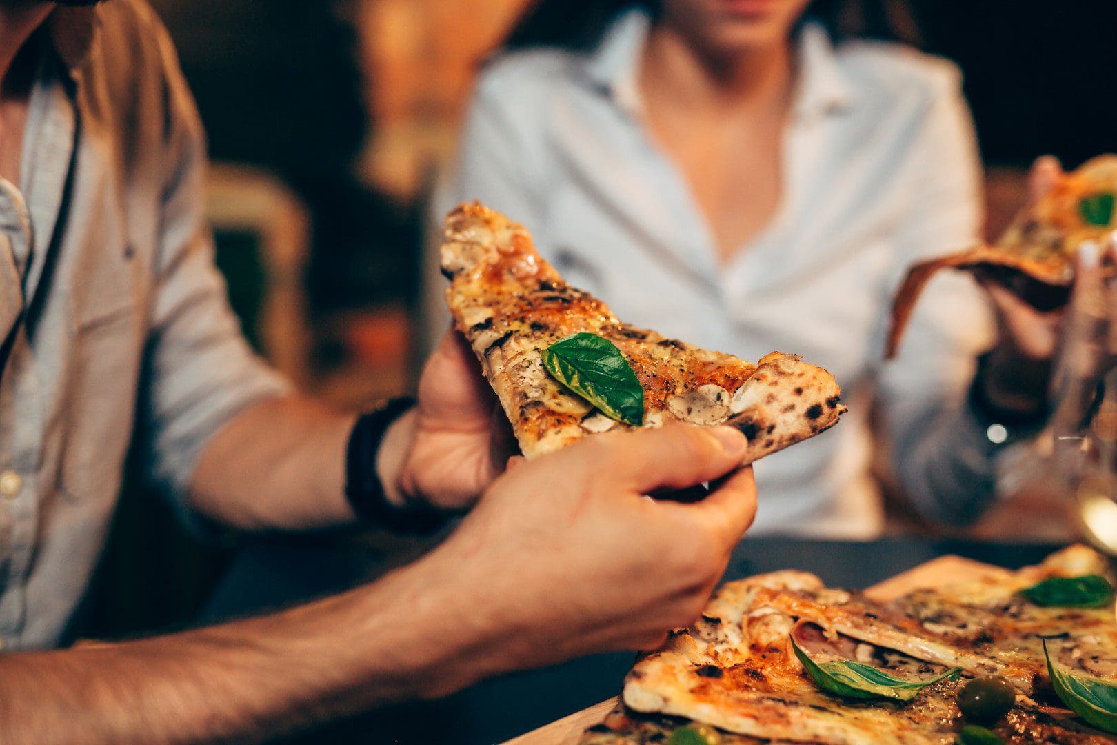 Friends enjoying pizza cooked in an outdoor pizza oven